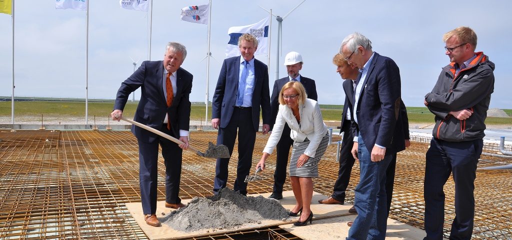 De buis gaat het fundament in: Groningen Seaports directeur Harm Post, EMO-directeur Knut Gerdes, EMO-projectleider Michael Baumfalk, de burgemeester van Eemsmond, Marijke van Beek, AG EMS-directeur Bernhard Brons, aannemer Jaap Kooi en Siemens projectmanager Gerard van Rijn.