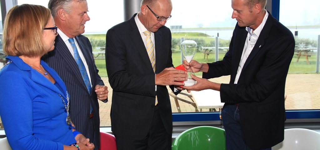 Joop Atsma, staatssecretaris van Infrastructuur en Milieu krijgt uit handen van Arjan Berkhuysen, directeur Waddenvereniging, een zandloper uitgereikt om symbolisch wat tijdsdruk en prioriteit te geven aan veiligheid in het Eemsdollardestuarium. Vlnr burgemeester Eemsmond: Marijke van Beek, Harm Post (directeur Groningen Seaports) en helemaal rechts Arjan Berkhuysen, directeur Waddenvereniging.