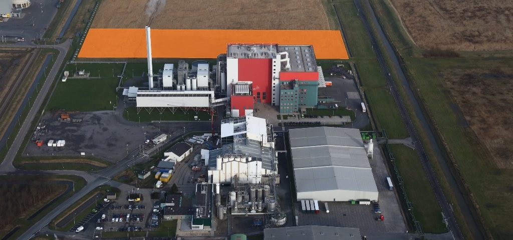 De afvalenergiecentrale EEW Energy from Waste (rode fabriek) met daarachter het uitbreidingsgebied (oranje vlak)
