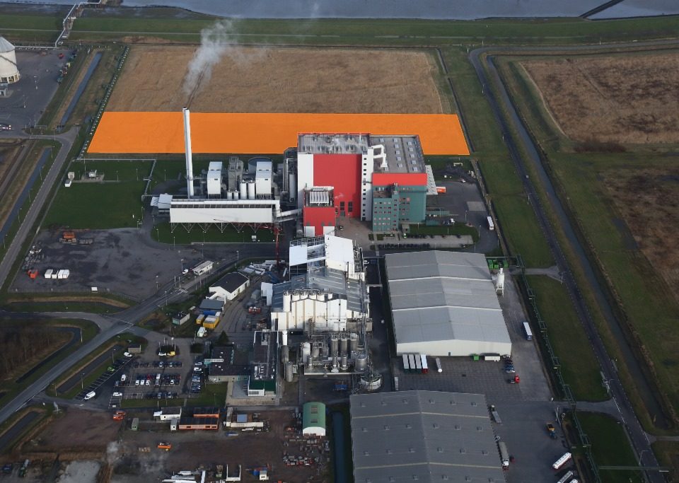 De afvalenergiecentrale EEW Energy from Waste (rode fabriek) met daarachter het uitbreidingsgebied (oranje vlak)