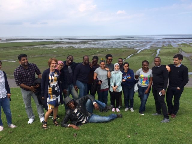De internationale studenten van UNESCO samen met Monique van den Dungen op de dijk in de Emmapolder